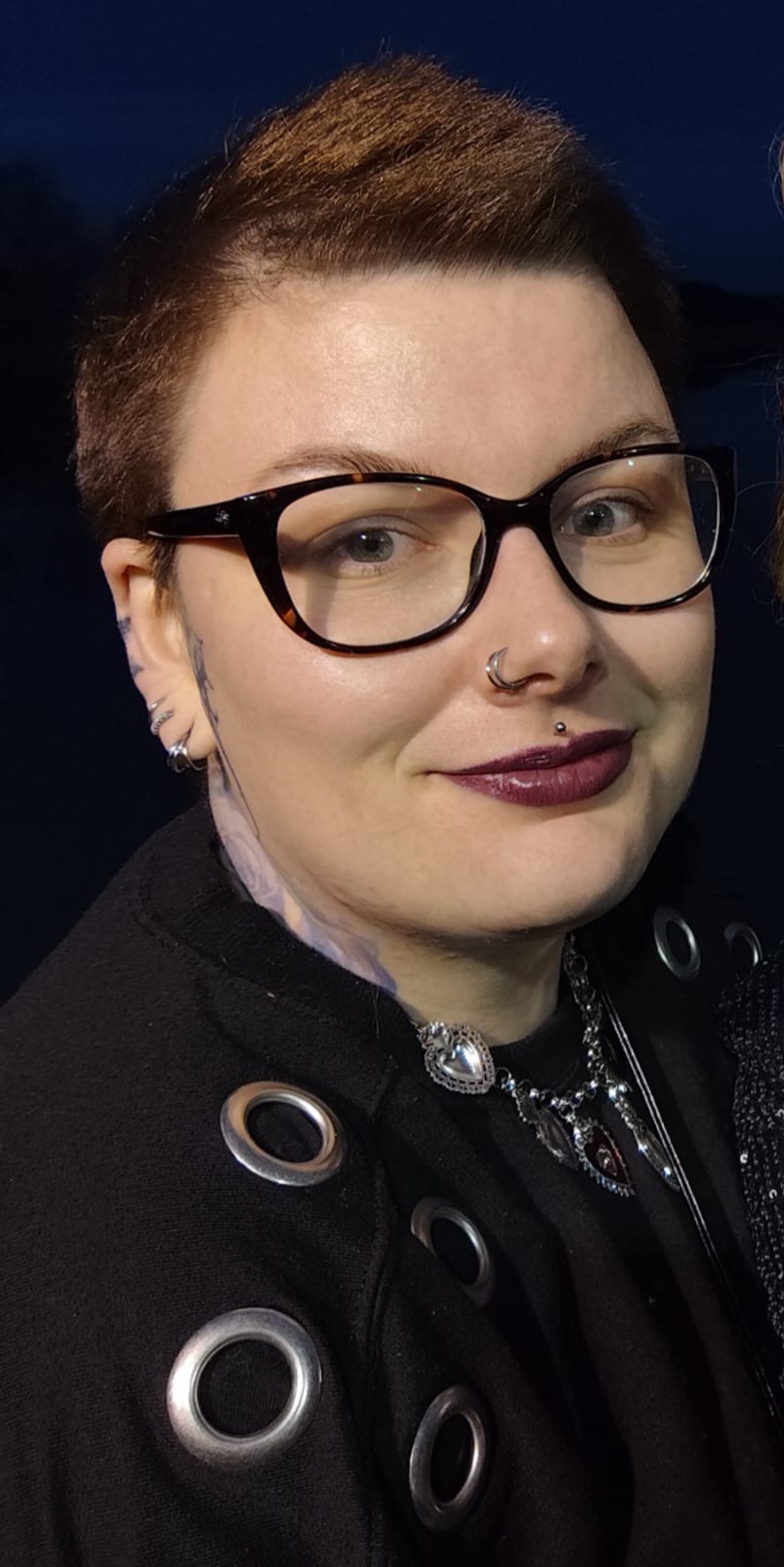 Une photo portrait d'Elisa, souriante, portant des lunettes, sur fond noir.
