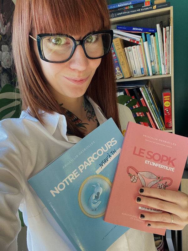 Priscillia, patiente atteinte de SOPK sévère, se prend en autoportrait. Elle tient dans sa main gauche ses deux livres : "SOPK et l’infertilité" et "Notre parcours jusqu’à toi".